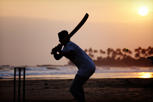 Boy playing cricket at sunset on tropical beach in Sri Lanka - Photo, Image