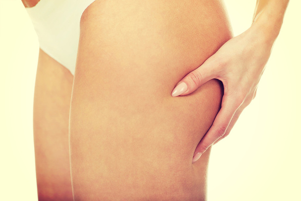 Slim woman pinching her thigh. - Fotografie, Obrázek