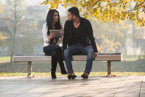 Hombre y mujer mira la tableta electrónica en el parque
 - Foto, imagen