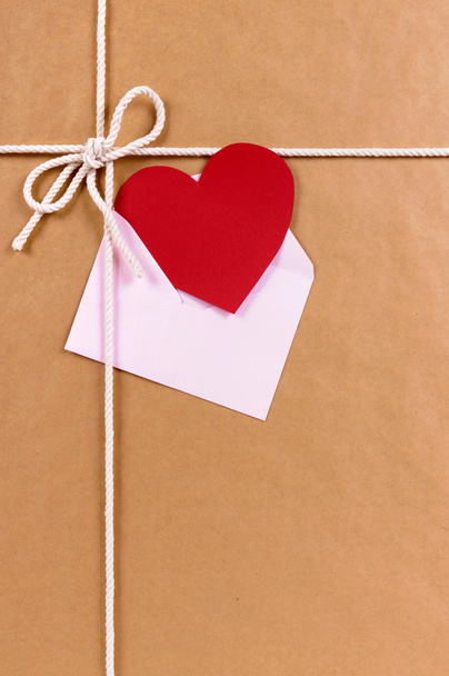 Regalo de San Valentín con tarjeta de corazón rojo o etiqueta de regalo, paquete de papel marrón
 - Foto, Imagen
