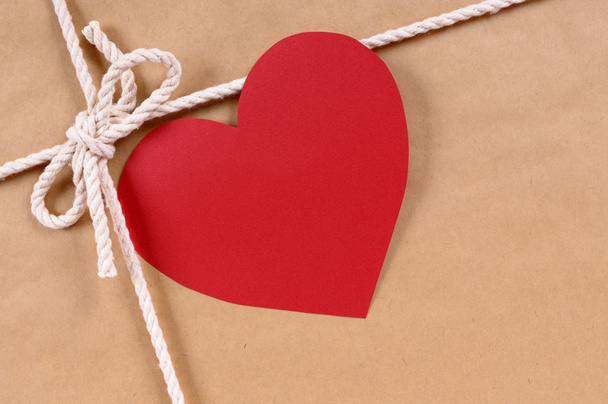 Подарок на день Святого Валентина с красной форме сердца подарочный знак, коричневый пакет бумаги
 - Фото, изображение