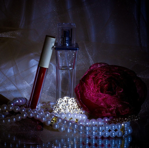Hajuvesipullot, punainen huulipuna, sulka, ruusu ja helmet helmiä
 - Valokuva, kuva