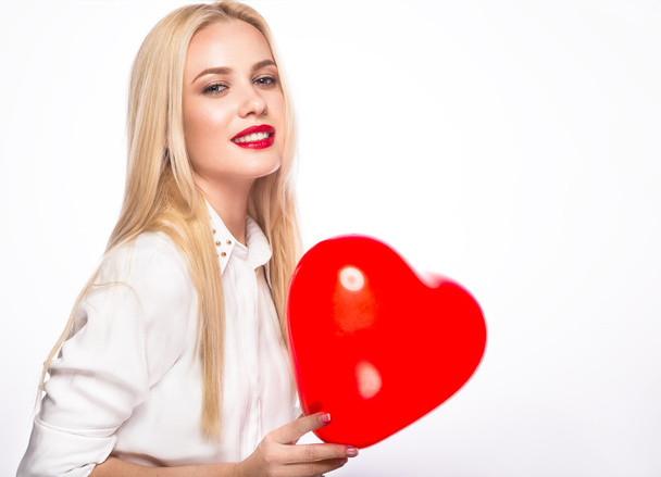 Portrait of Beautiful blond woman with bright makeup and red heart in hand. valentines day - Фото, изображение