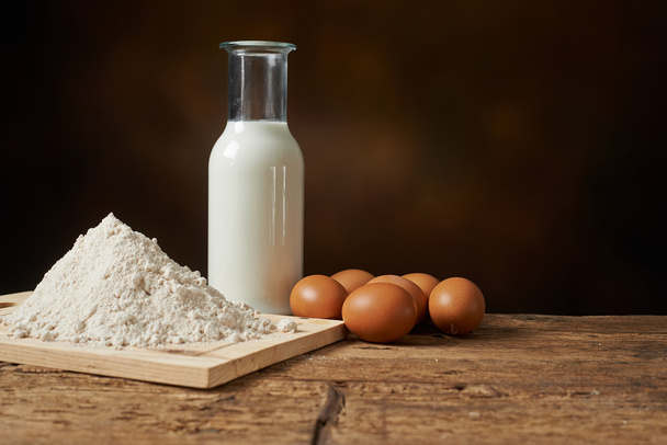manufacturing materials, flour eggs and milk on a wooden kitchen - Foto, afbeelding