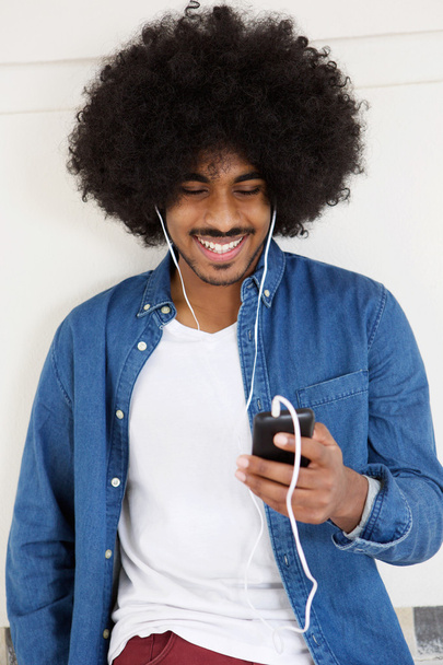 Крутой парень улыбается с мобильного телефона и наушников
 - Фото, изображение