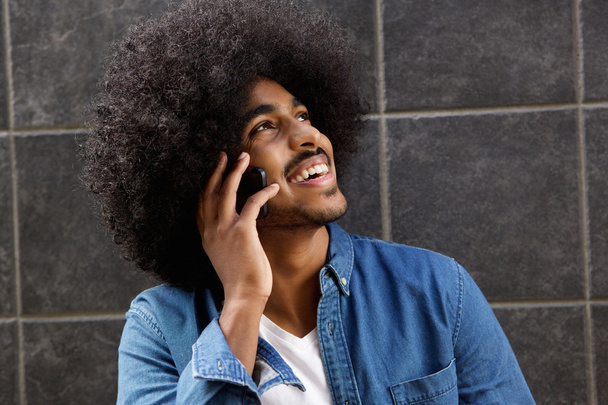 Happy black guy talking on mobile phone - 写真・画像