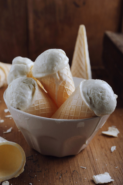 Conos de helado de vainilla en cuenco sobre fondo vintage de madera
 - Foto, imagen