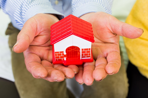 Foto de uma casa em miniatura segurando as mãos
 - Foto, Imagem