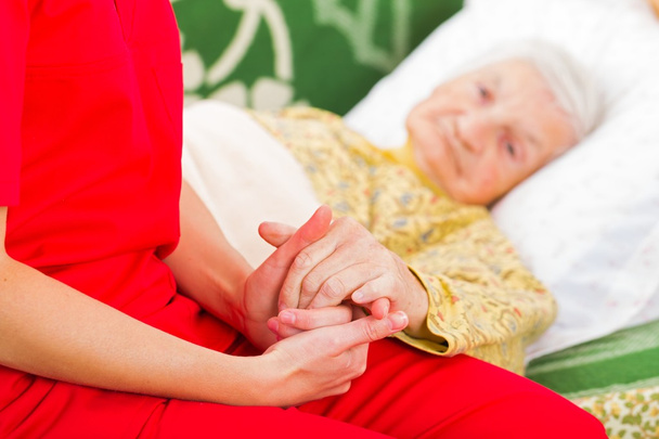 Junge Pflegerin gibt der alten Frau helfende Hände - Foto, Bild