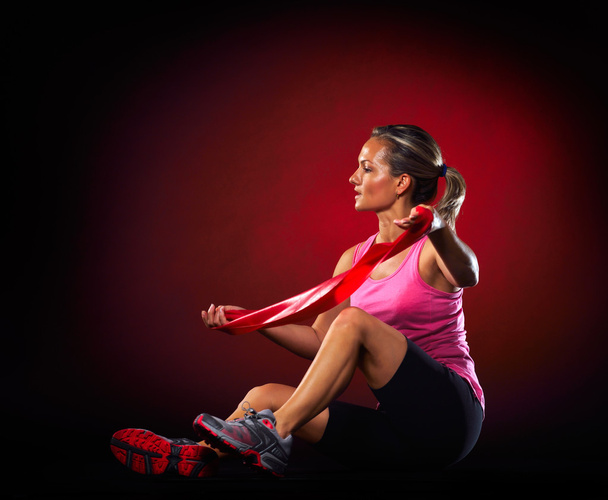 mujer joven haciendo ejercicio con banda elástica de fitness en el gimnasio
 - Foto, Imagen