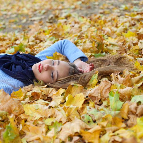 girl lying among yellow leaves - Фото, зображення