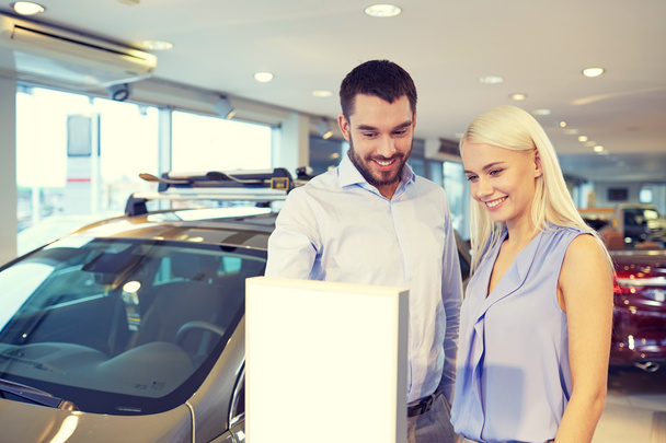 happy couple buying car in auto show or salon - Фото, зображення