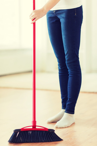 close up of woman legs with broom sweeping floor - Foto, afbeelding