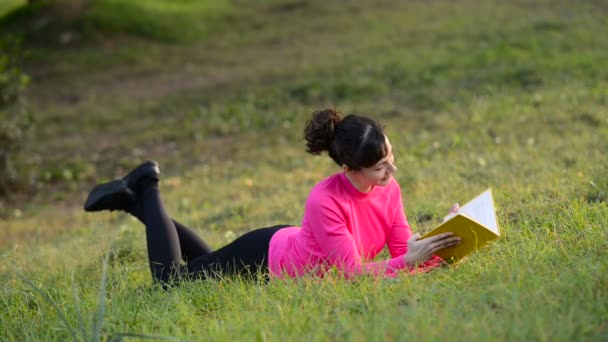 young woman reading book lying in the meadow - Footage, Video
