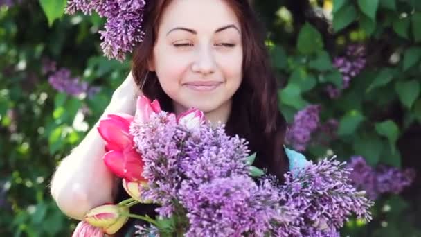 Νεαρή γυναίκα με λιλά στεφάνι. Γυναίκα με λουλούδια πασχαλιά - Πλάνα, βίντεο