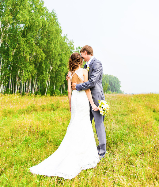 Fiatal esküvői pár élvezi a romantikus pillanatokat kívül a nyári réten. - Fotó, kép
