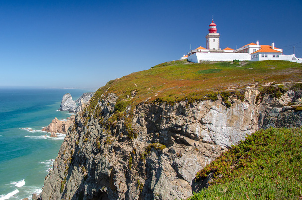 Lighthouse stands on a high promontory on the shores of the ocean - Fotoğraf, Görsel