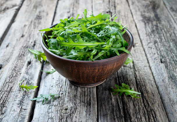 Fresh rucola in a bowl on a rustic wooden table. - Photo, Image