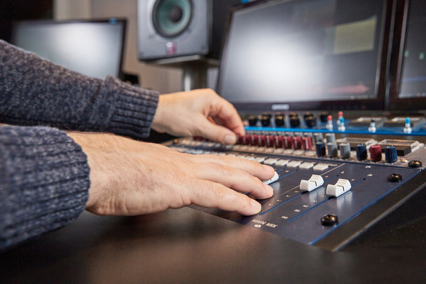 Side view of hands of audio engineer mixing on console - Foto, Imagen
