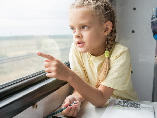 Girl shows a finger in the second-class car of a train window - Photo, Image