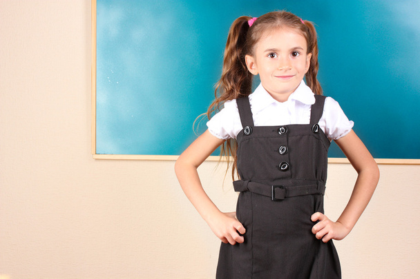 Beautiful little girl standing near blackboard in the classroom - Foto, imagen