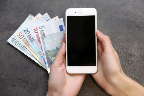 Hands with smart phone and euro banknotes on grey background. Making money online - Fotoğraf, Görsel
