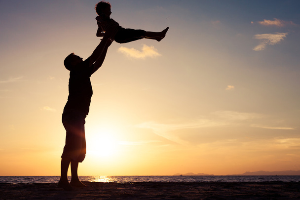 Père et fils jouant sur la plage au coucher du soleil
.  - Photo, image