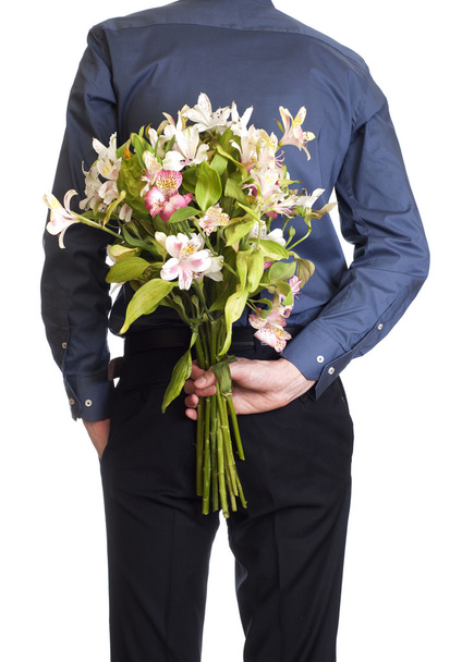 Man hold bouquet bouquet of flowers behind his back. isolated o - Photo, image