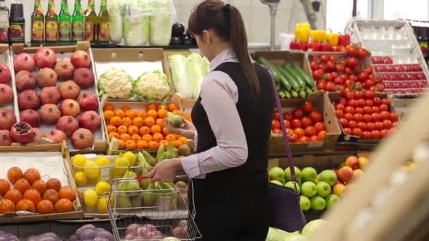 Woman selecting fruit at market and adds to cart, rear view - Filmati, video