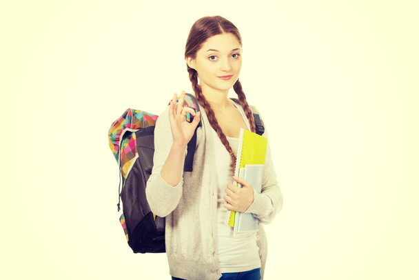 Teen woman with backpack showing perfect sign. - 写真・画像