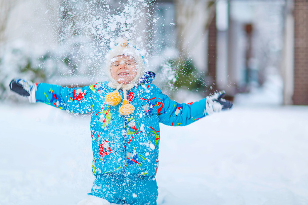 Маленький мальчик играет со снегом зимой, на открытом воздухе
 - Фото, изображение
