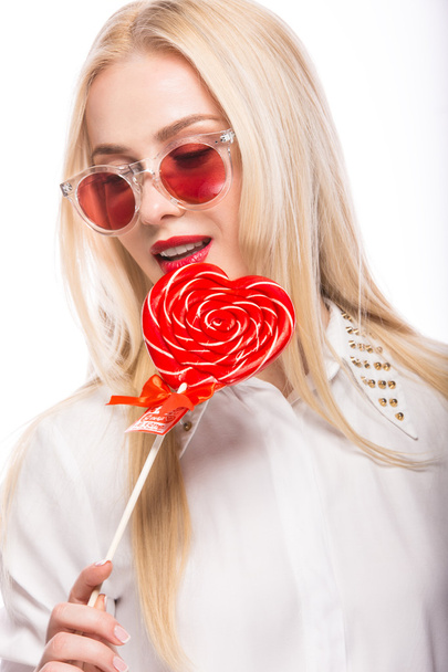 Portrait of Beautiful blond woman with bright makeup and red candy heart in hand. valentines day - Foto, Imagem