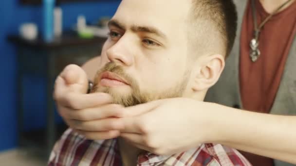 Barber rubs his beard client butter - Materiał filmowy, wideo