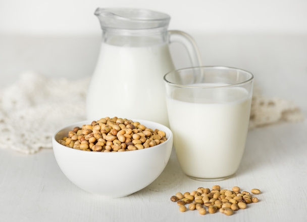Soy milk  and soybeans on a white table - Zdjęcie, obraz