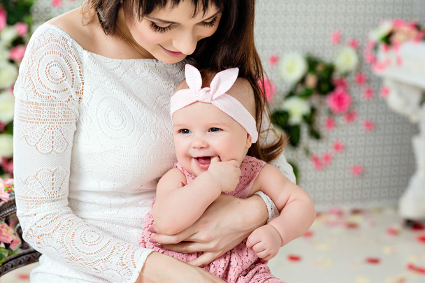Beautiful and happy mom brunette in a white dress holding on the - Fotoğraf, Görsel