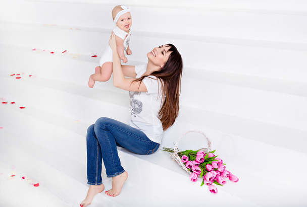 Beautiful and happy mom brunette in white t-shirt and jeans thro - Fotoğraf, Görsel