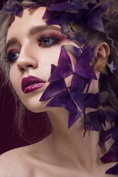 Creative fashionable image, girl with a bright make-up and purple plant on her face. - Foto, immagini