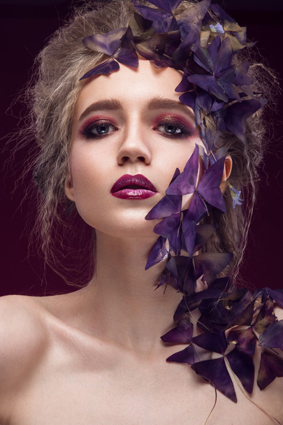 Creative fashionable image, girl with a bright make-up and purple plant on her face. - Фото, зображення
