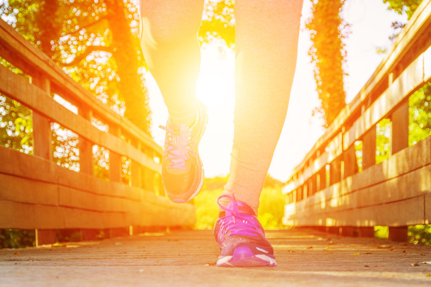 Nainen juoksee auringonlaskun aikaan pellolla
 - Valokuva, kuva