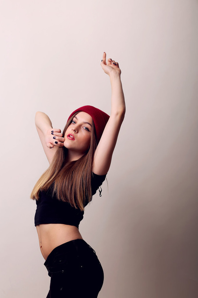 happy girl standing in a studio on beige background, cap on head, model posing, red lips - Foto, immagini