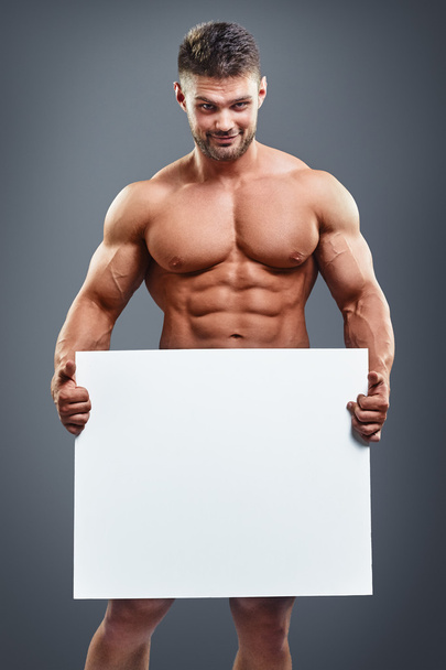 bodybuilder holding blank white poster - Foto, Imagem