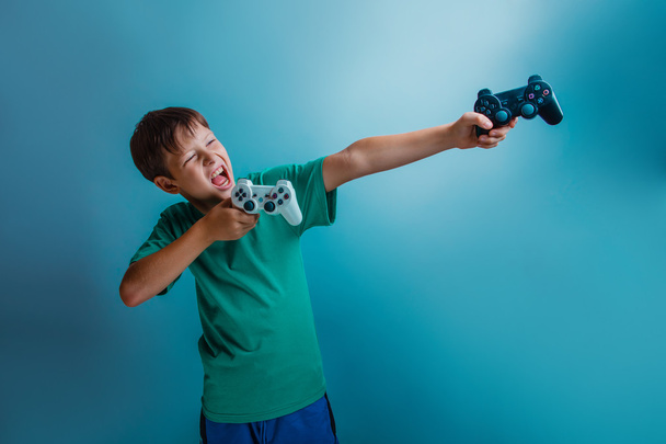 een jongen van twaalf Europese uiterlijk houdt een gaming joystick openen - Foto, afbeelding