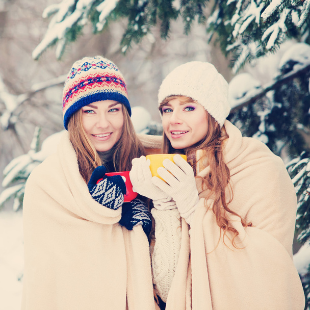 Two young women with colorful cups drinking tea outdoor and smil - Foto, afbeelding