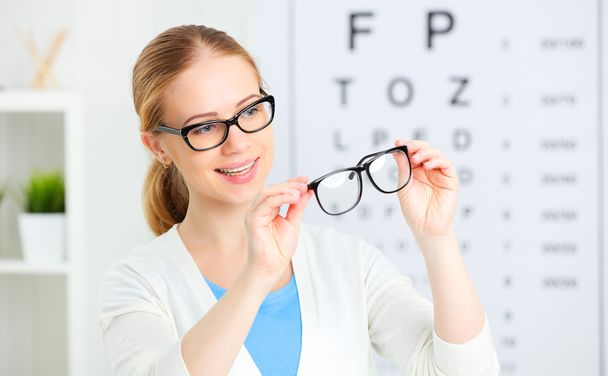 eyesight check. woman choose glasses at doctor ophthalmologist o - Foto, afbeelding