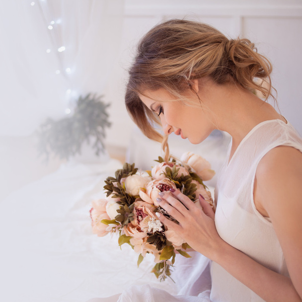 beautiful woman model with fresh daily makeup and romantic wavy hairstyle, holding a bouquet of flowers - Photo, Image