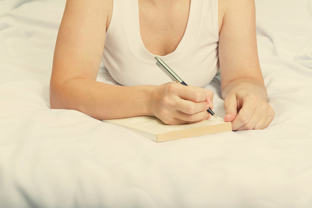 Mujer joven en la cama con cuaderno
.  - Foto, imagen