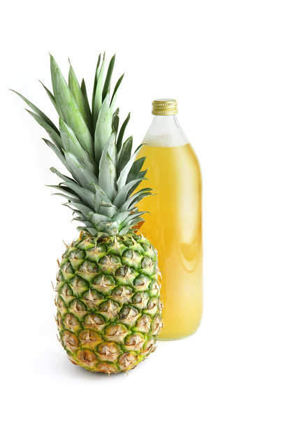 Glass bottle of juice next to pineapple - Fotó, kép