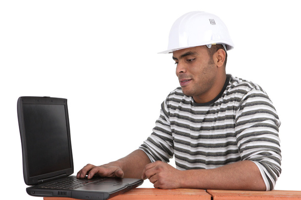 Builder sat using laptop - 写真・画像