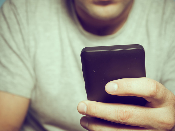 Joven hombre caucásico en un teléfono inteligente camiseta gris
  - Foto, Imagen