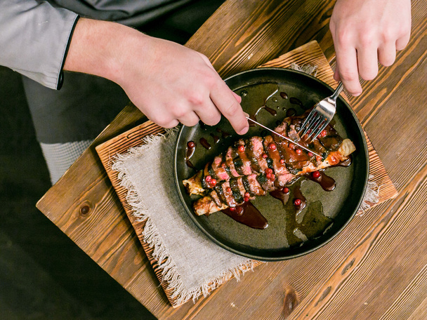 Carne roja (ternera, venado), manos masculinas sosteniendo un cuchillo y un tenedor
 - Foto, Imagen